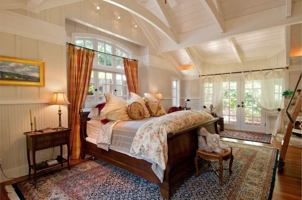 Country bedroom with a large bed positioned in front of a window.