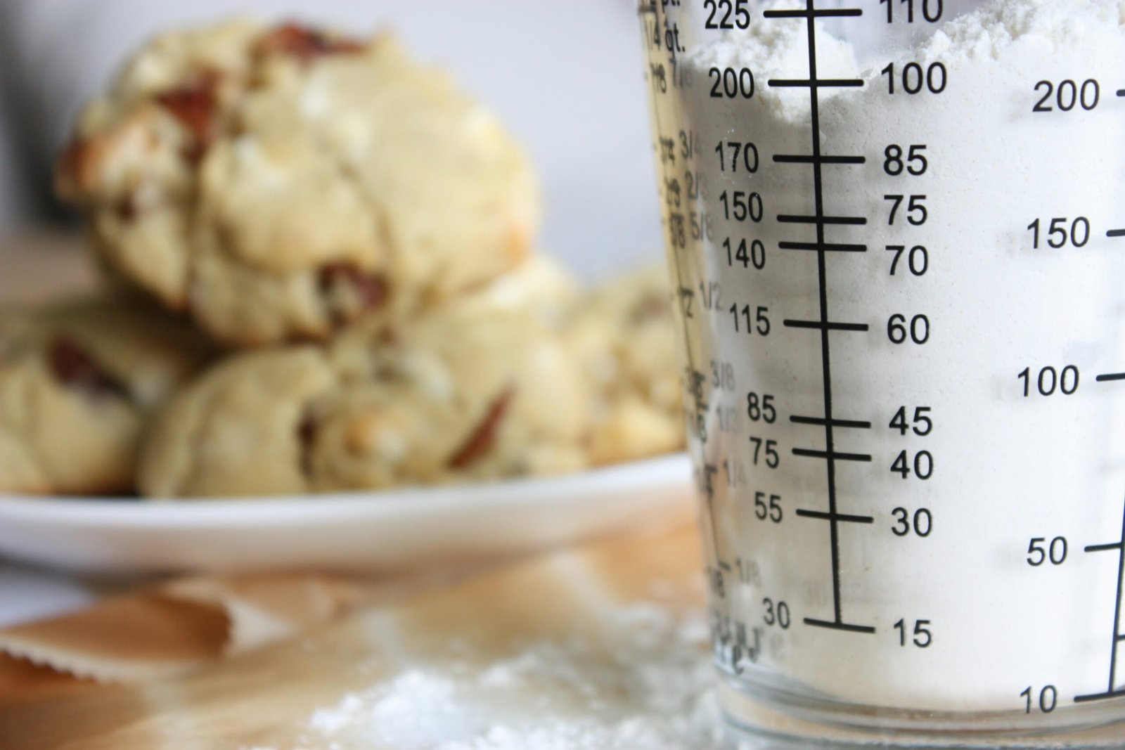 A class measuring cup with a plate of cookies